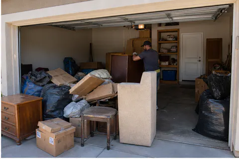 Garage junk removal cleanout with furniture, cardboard and bagged trash ready for removal