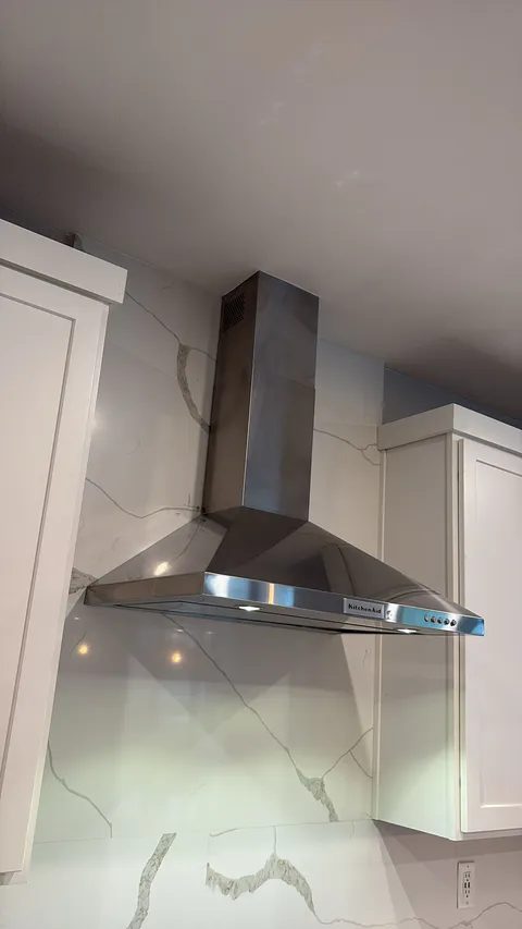 Kitchen hood and backsplash detail showing stainless steel ventilation and finished wall tile